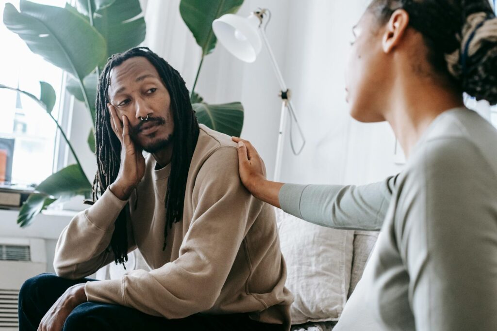 Ethnic psychologist touching black depressed clients shoulder empathy